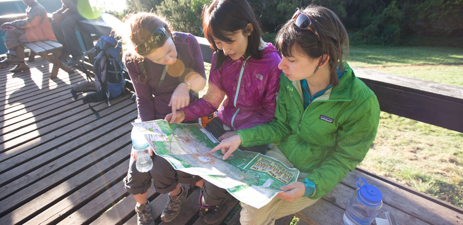 female hikers looking at a map and planning out their backpacking trip